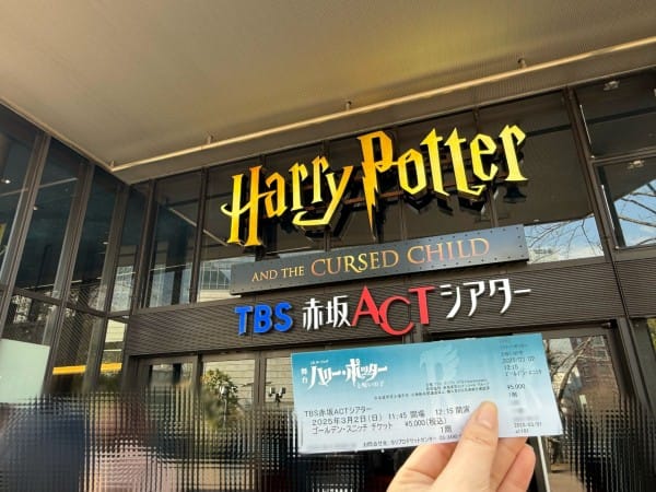手持門票與劇場入口標示的合影