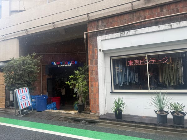 一番街上兩家相鄰的古著店，右邊櫥窗掛著粉色霓虹燈與一整排牛仔褲