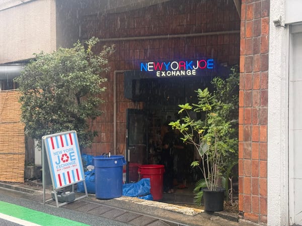 New York Joe Exchange 的入口，磚牆上一道深色門洞，上方有霓虹招牌