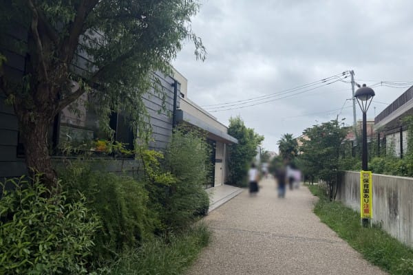 下北線路街的碎石步道，兩側是低矮的店鋪與綠植，遠處有行人