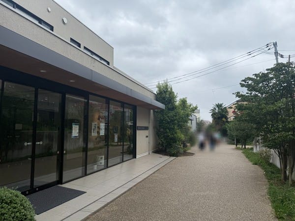 沿著小田急舊鐵道用地鋪設的步道，左側是一棟低矮的玻璃帷幕建築，右側有植栽