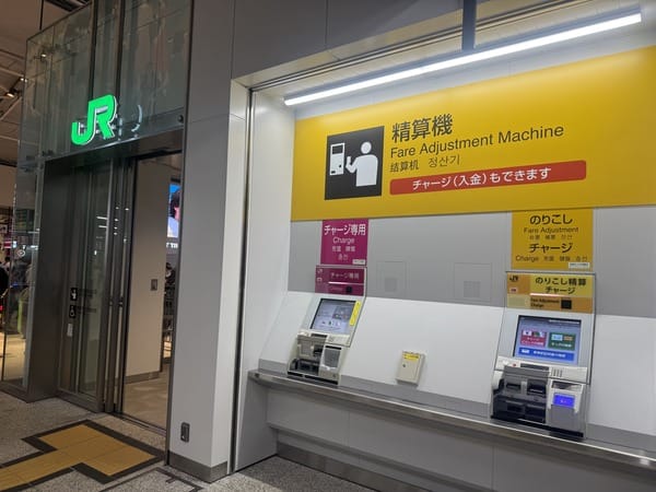 JR車站閘門旁的精算機專區，黃色招牌標示精算機Fare Adjustment Machine，右下角為のりこし精算機，左邊為粉紅色チャージ専用機